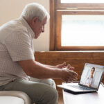 An elderly man is on a telemedicine call for his post-discharge follow-up appointment from a hospital.